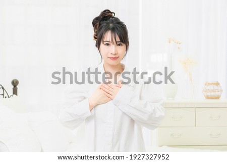 Young woman in a white shirt putting her hand on her chest in the room Foto stock © 