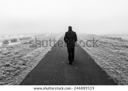 Man walking away on an empty desolate raod