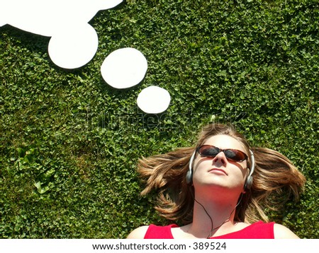 woman with headphones lying on grass with cartoon thought bubble over head