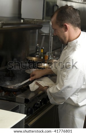 Caucasian chef in a smoky restaurant kitchen cooks Ahi Tuna.