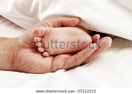 Dad holding baby feet in white sheet