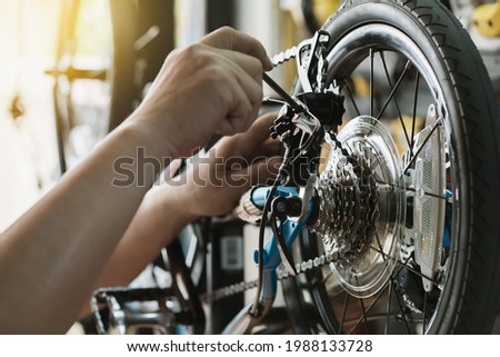 Bike mechanic repairs folding bicycle in Workshop. adjust Rear Derailleur ,cassette sprocket . Bicycle Maintenance and Repair concept