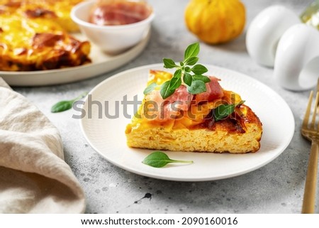 A piece of frittata with pumpkin, bacon and ricotta in a ceramic plate on a light culinary background. Traditional Italian delicious homemade egg dish on the kitchen table closeup	 Foto d'archivio © 