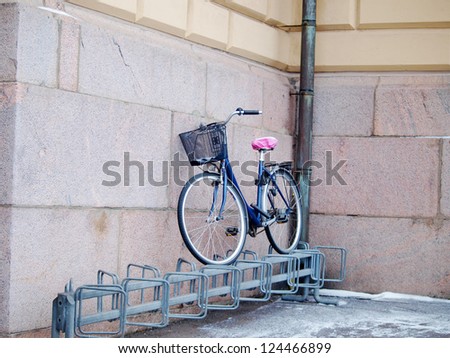 Bike left above a bike rack, towards a stone brick building