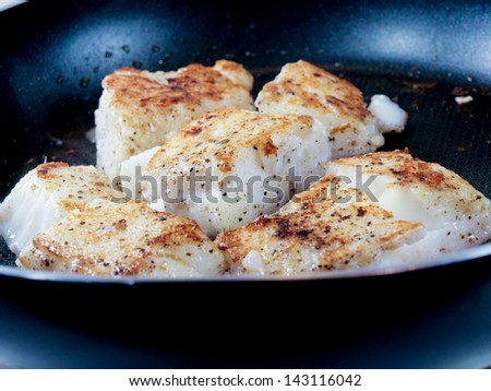 Someone frying seasoned white fish in a frying pan