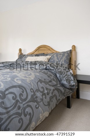 double bed with hard wood bed frame and abstract motif bedsheets