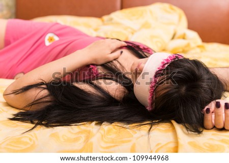 Sleeping young woman in sleep eye mask on yellow furnishing