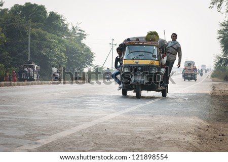 AGRA, INDIA - NOV 15: Overloaded motorcycles, cars and tuk-tuks drive on hazy Ring road (Delhi - Agra) on Nov 15, 2012 in Agra, India. More than ten person on one tuk-tuk is very widespread in India.