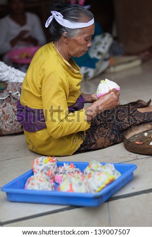 TAMPAK SIRING, BALI, INDONESIA - SEP 21: Woman makes sweets for balinese traditional offerings to gods in temple Puru Tirtha Empul on Sep 21, 2012 in Tampak Siring, Bali, Indonesia