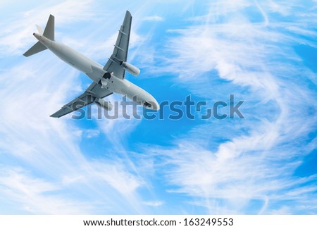 White jet airplane fly in blue bright wispy cloudy blue sky