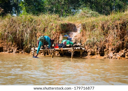 Burmese person wash up cloth in Inle lake canal water.