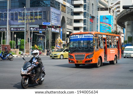 BANGKOK, THAILAND - 21 NOV 2013: Public transport bus and motorbike pass crossroads street with modern buildings on background