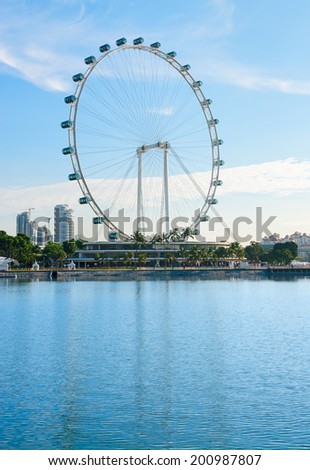 Big ferris wheel in the modern city skyline and bay water on front, Singapore.