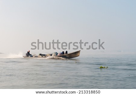 INLE LAKE, MYANMAR (Burma) - 07 JAN 2014: People transportation wooden long boat with motor fast move on blue water. Boats is a key transport type on Inle lake.