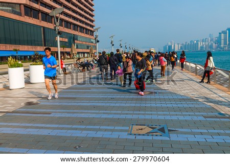 HONG KONG, CHINA - 18 JAN 2015: Tourists strolling along  the Avenue of the Stars at Kowloon Promenade, with a view of the Hong Kong skyline in the background.