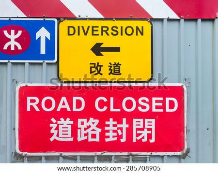 Brightly colored traffic signs announce a detour due to construction and development along a central street in downtown Hong Kong, China.