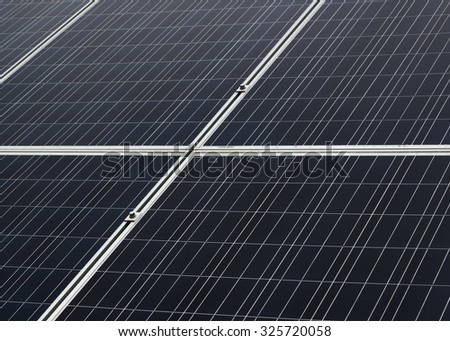 Closeup of outdoor solar panel. The solar panel is the type used to power signs and equipment along highways. Some drops of water are on the surface from rain, and there are faint cloud reflections.