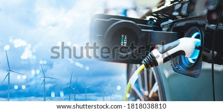 Double exposure of vehicle electric car charge battery with wind turbine and blue sky blur bokeh on panoramic background. Idea nature electric energy to generate electricity. Green energy eco concept.
