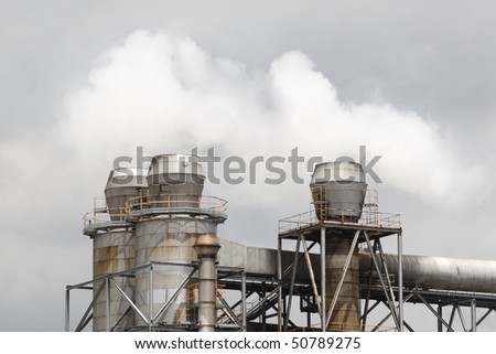Factory detail. Group of chimneys. Part of manufacturing plant against cloudy sky