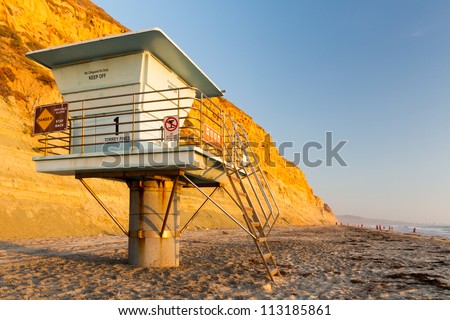 Lifeguard tower in front of a large cliff with the glow of the evening sun.