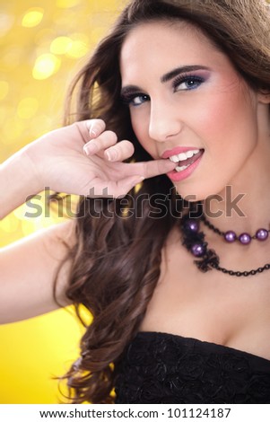 Close-up portrait of an attractive young woman with finger in mouth against colored background