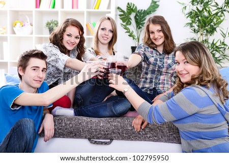 Group of teenagers on private party with raised glasses after a toast