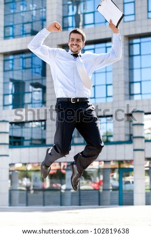 Jumping happy businessman over office buildings
