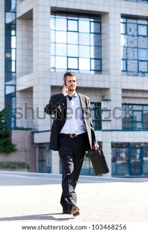 Successful businessman doing business on mobile phone, full length