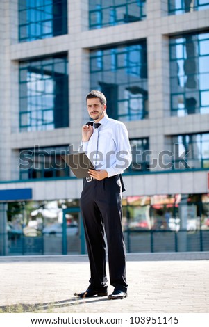 busy businessman with documents front of office building