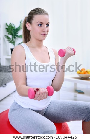 woman lifting dumbbells while sitting on a yoga ball