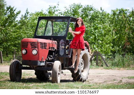 Young attractive girl on tractor, country life