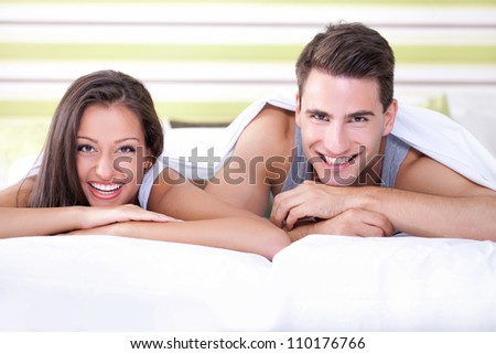 Romantic and cute young couple laughing in bed