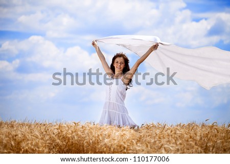 Pretty woman in golden wheat field with flying scarf