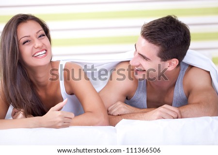 happy young couple lying in bed and laughing
