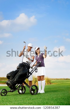 young couple playing golf at the club, choosing  sticks out of the golf-bag