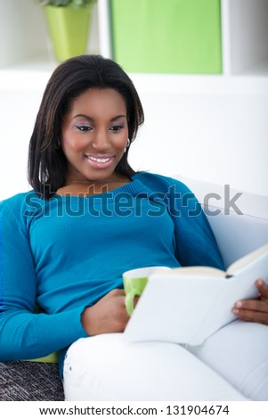 Smiling black woman reading interesting book