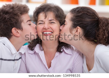 Adorable siblings kissing their mother