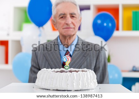senior man with birthday cake with a question mark candle on it