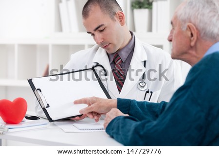 Senior man consulting with doctor and pointing at empty paper