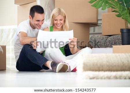 Man and woman looking at their house plans sitting in their new house