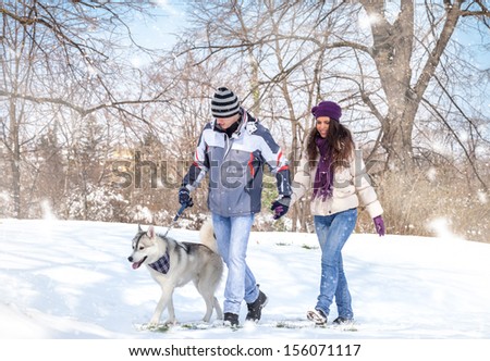 young couple walking his dog in a winter day