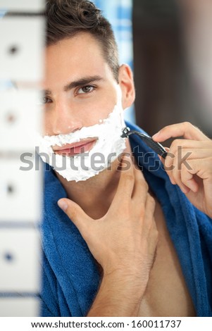 Close-up shot with a reflection in the mirror of a man during his shaving