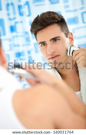 young man shaving his beard off with an electric shaver