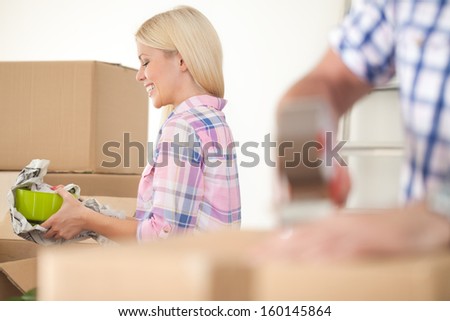 Women packing some household things in moving boxes