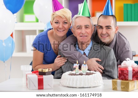 Portrait of happy family front of birthday cake for 70th birthday