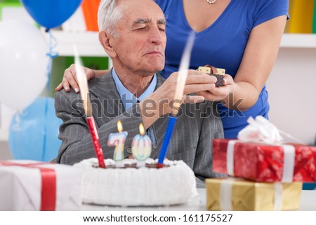 senior man celebrating 70th birthday and receiving birthday gift