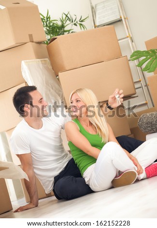 Couple moving into new home with door keys and boxes