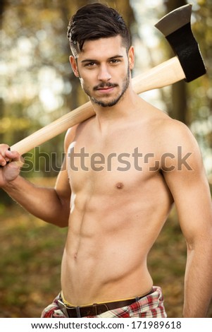 Young fit lumberjack holding an ax over his shoulder