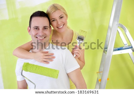 Young affectionate,  happy handy couple painting new house