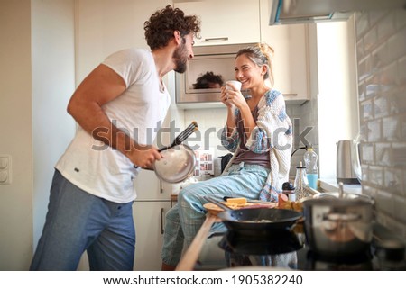 A young couple in love having good time while preparing a breakfast together on a beautiful morning. Cooking, together, kitchen, relationship